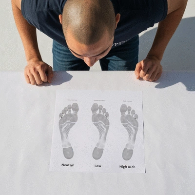 Person performing a wet test to determine foot arch type, showing different footprints