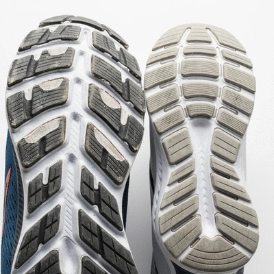Close-up of a worn-out running shoe sole next to a new one, highlighting wear