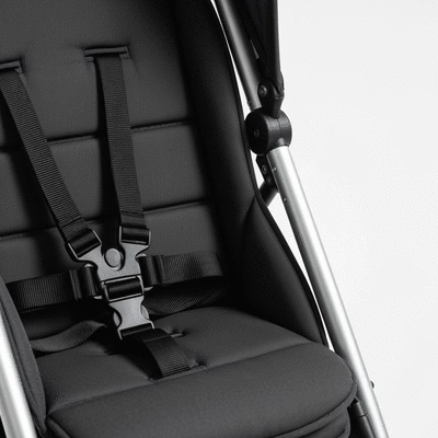 Close-up of a baby stroller's five-point harness and brake system